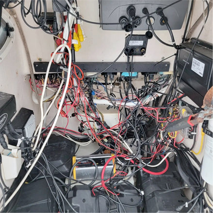 Photo of a dangerous, tangled mass of wires and unsafe marine electrical components.
